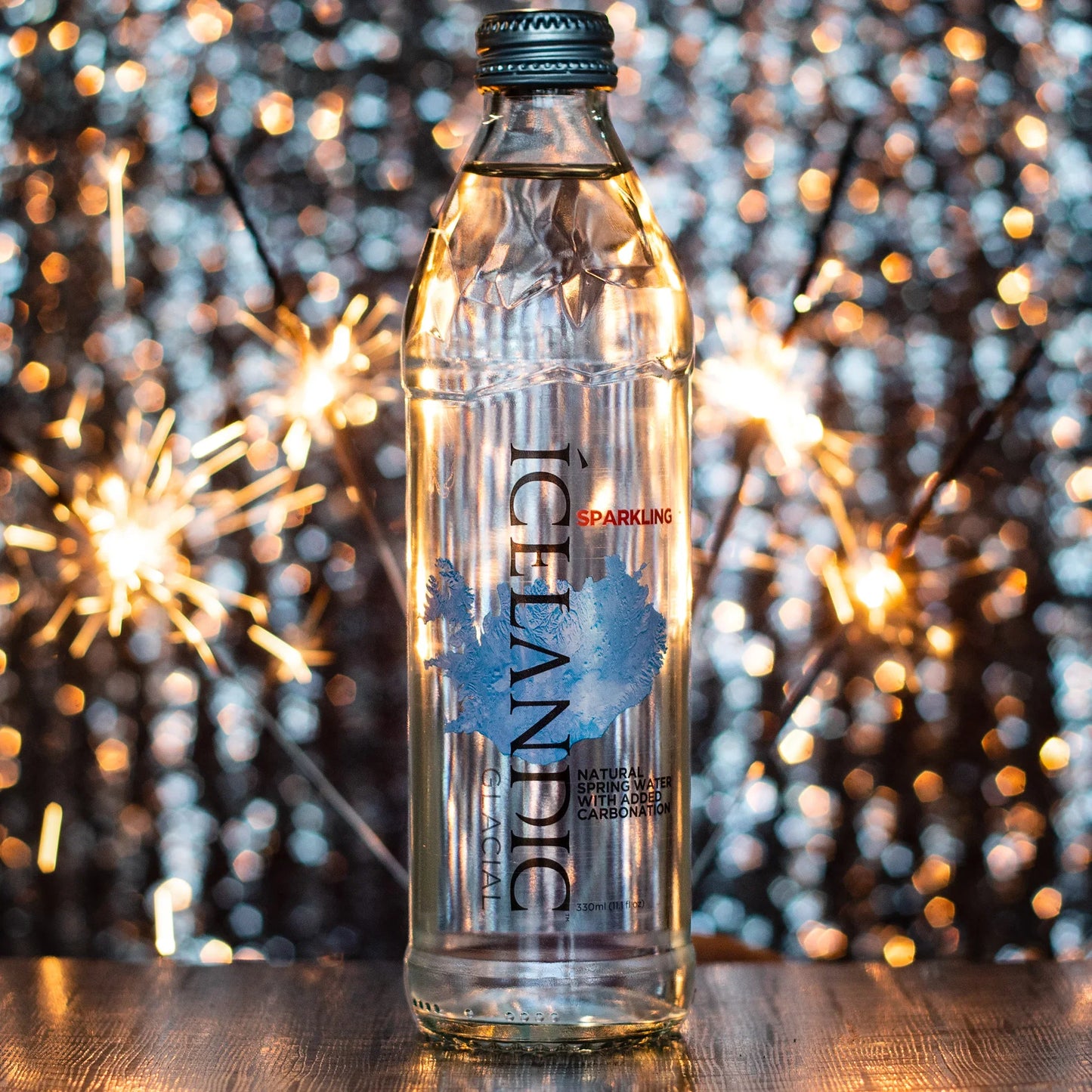 Sparkling Icelandic spring water bottle on table with bright bokeh lights background